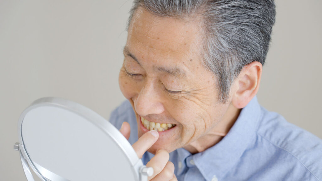笑顔で鏡を見る高齢男性