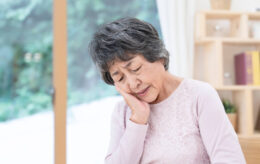 歯を押さえて悩む高齢女性