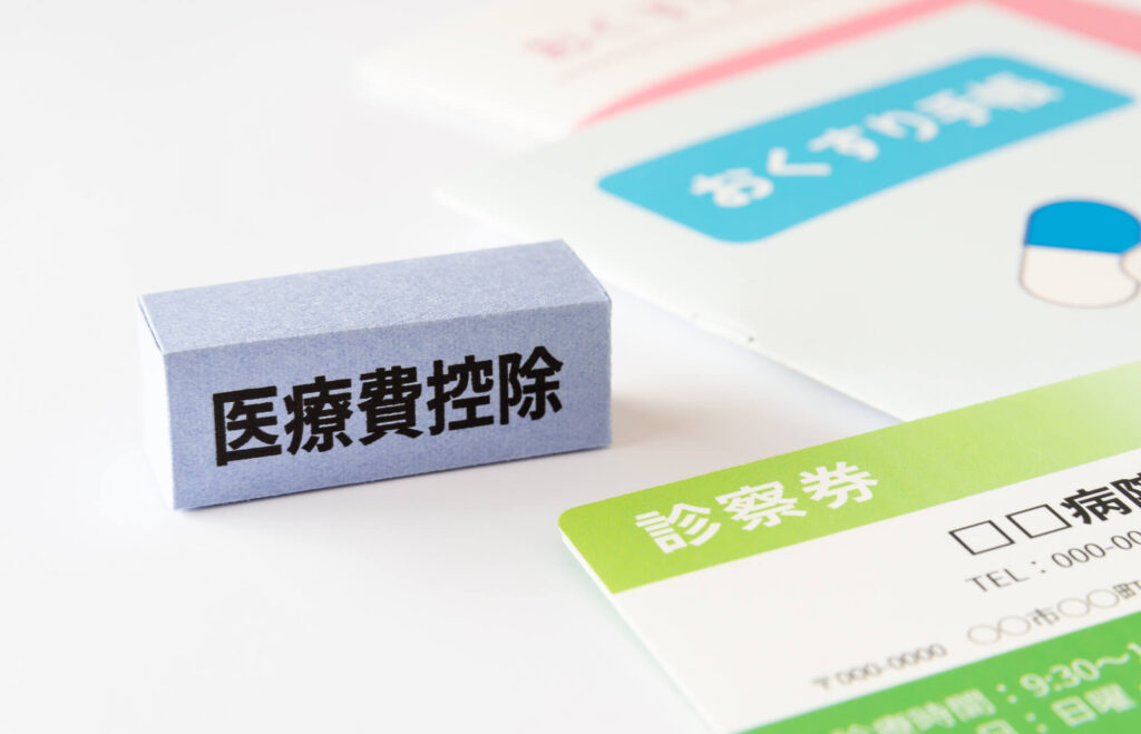 「医療費控除」と書かれたブロックと診察券・おくすり手帳