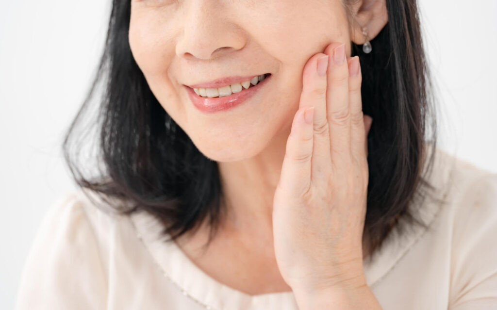 頬に手を当ててほほ笑む人の口元