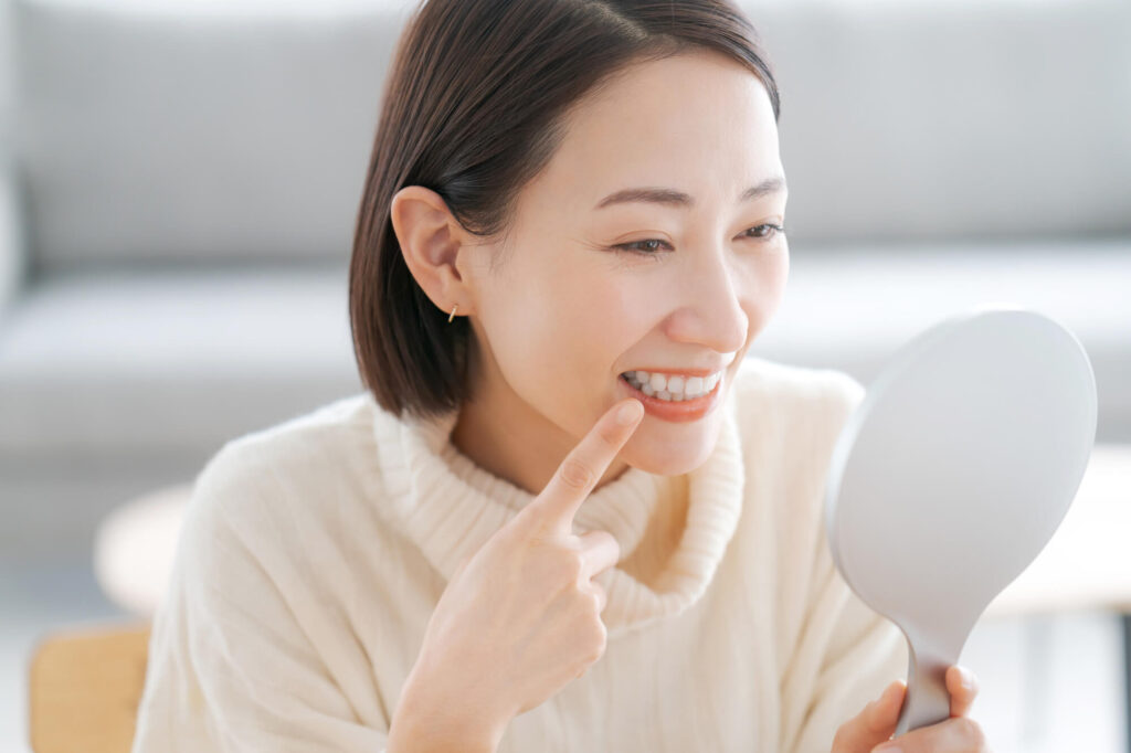 歯並びを手鏡で確認する女性