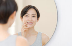 鏡の前で歯を気にする女性