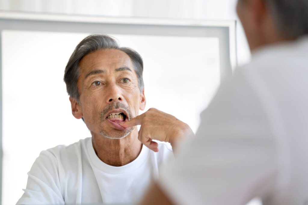 鏡の前で歯ぐきを気にする男性